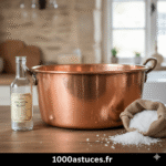une bassine ancienne en cuivre brillante, avec une bouteille de vinaigre blanc et un sac de gros sel à côté.Astuce nettoyer le cuivre